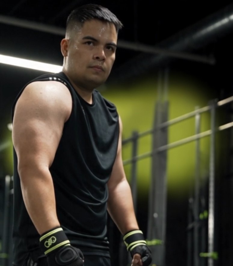 James Jefferson Flores Manipis in a black sleeveless shirt and wrist wraps in a gym lit with a green glow